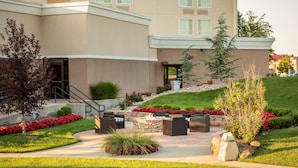 A modern hotel with a landscaped courtyard, outdoor seating area, and a stone fire pit. - Holiday Inn Wichita East I-35 by IHG (Wichita)