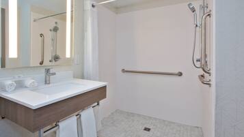 A modern bathroom with a white sink, a mirror, and a shower with a handheld showerhead.