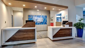 A reception area with two wooden reception desks, a blue geometric wall, and a potted plant.