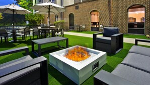An outdoor patio with a fire pit, seating, and umbrellas.