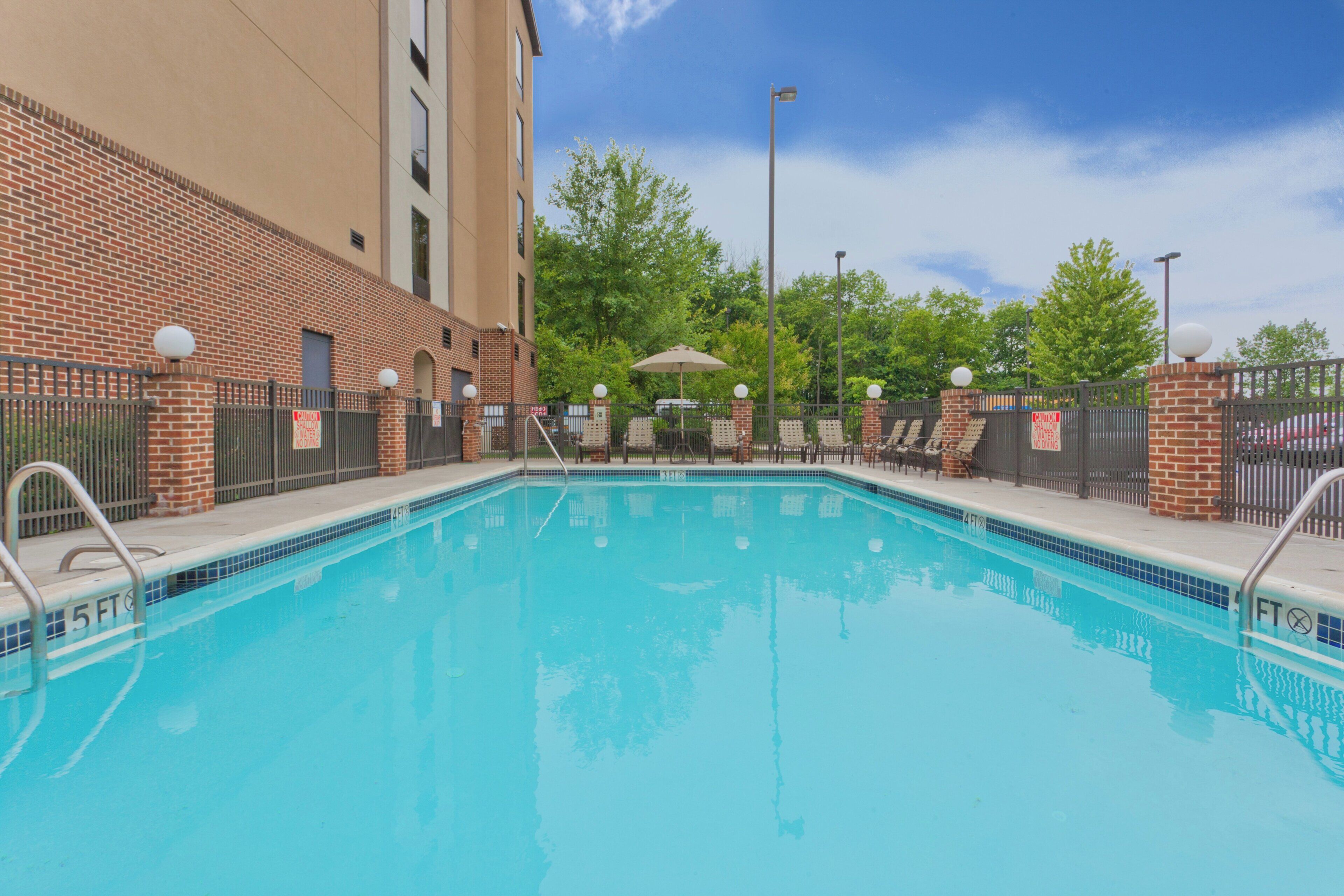 A swimming pool with a brick wall, a covered seating area, and a fenced poolside.