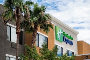 Un bâtiment de l’hôtel Holiday Inn Express, doté d’un design moderne, de grandes fenêtres et de palmiers à l’avant.