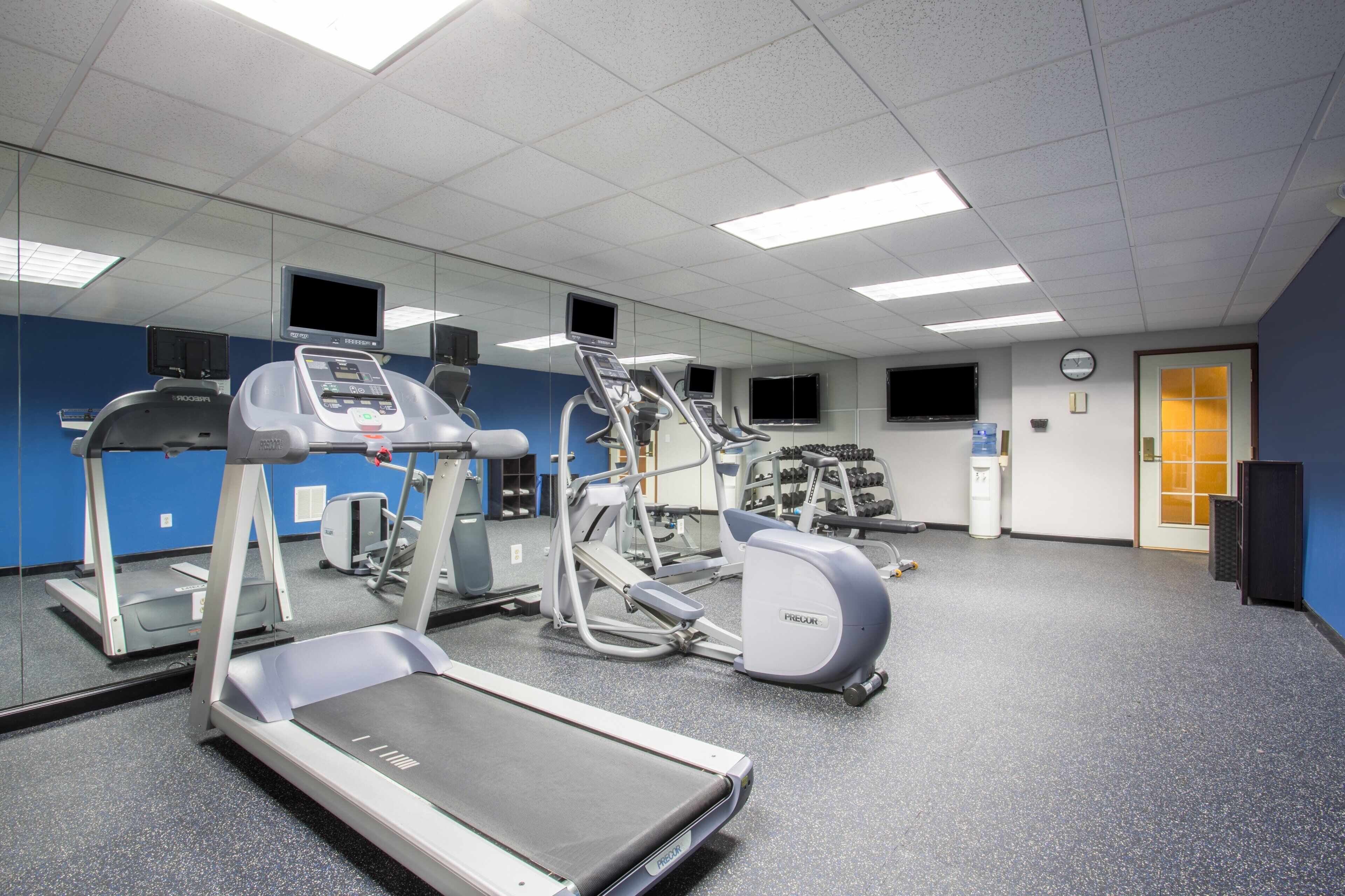 Un gimnasio con cintas de correr, elípticas y equipo de pesas.