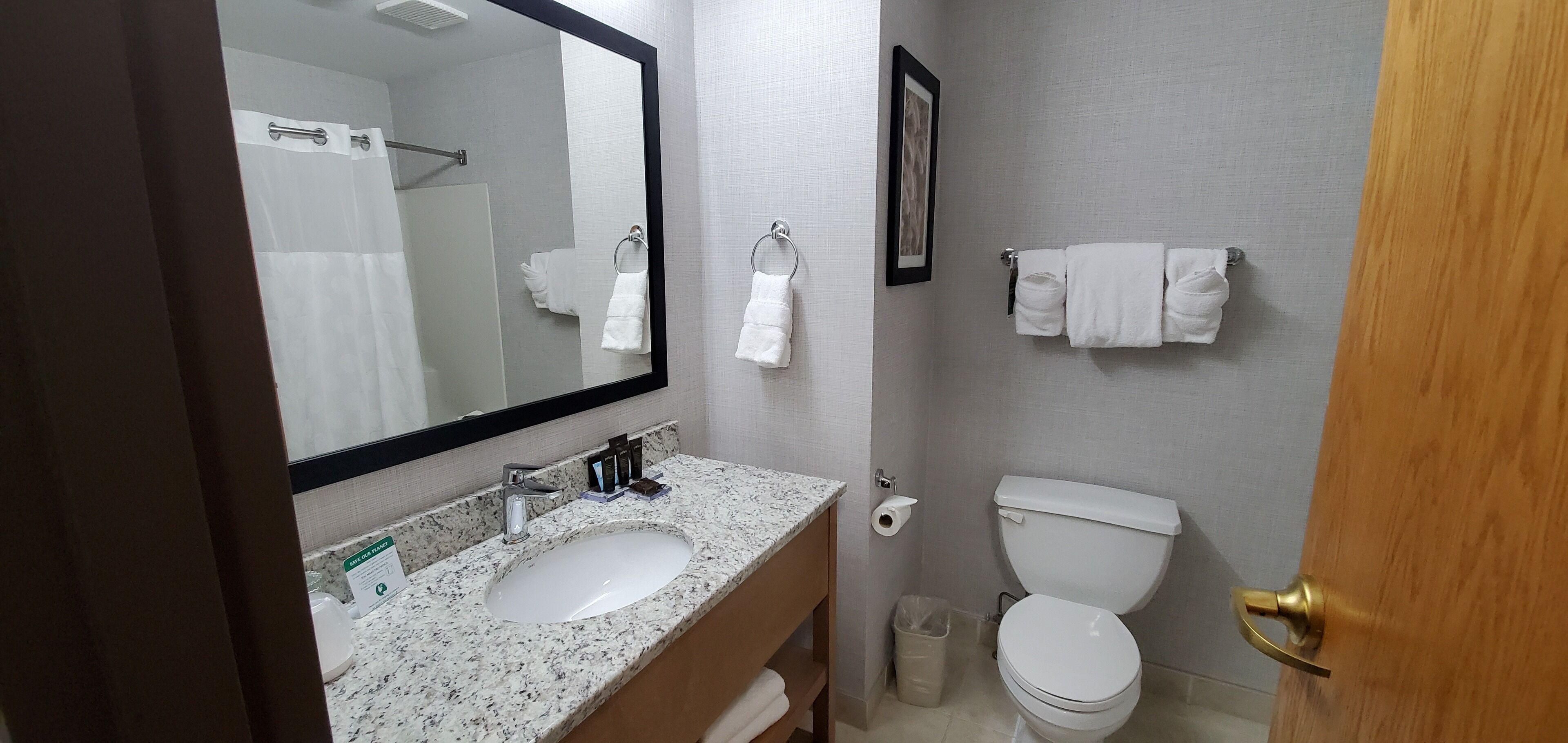 Un baño con lavamanos, espejo, inodoro y toallero.