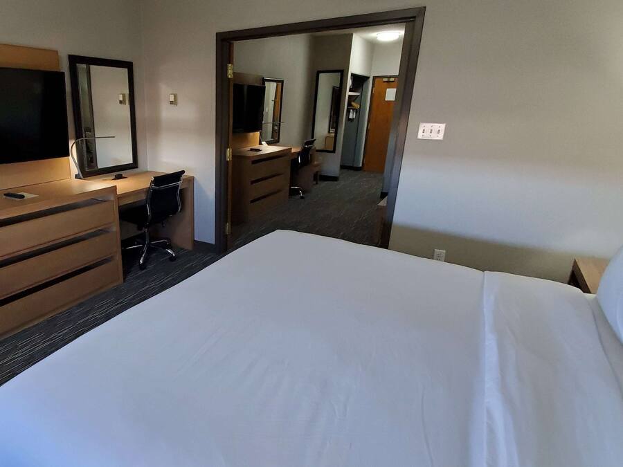 Habitación de hotel con una cama grande, un escritorio con silla, cómoda y televisor.