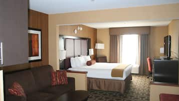 Una habitación de hotel con cama, escritorio, televisor, sofá y una mesa de centro.