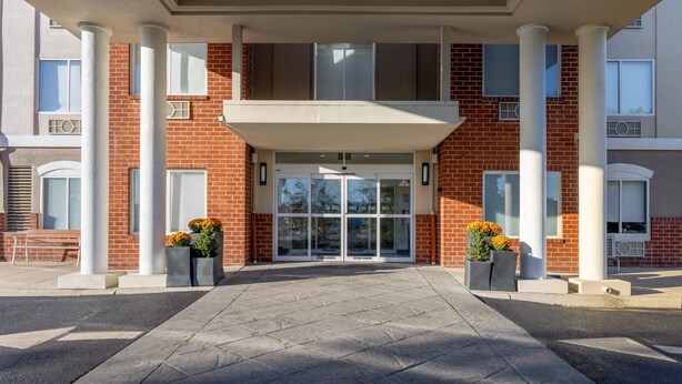 A building entrance with a brick facade, large columns, and a covered entrance area.