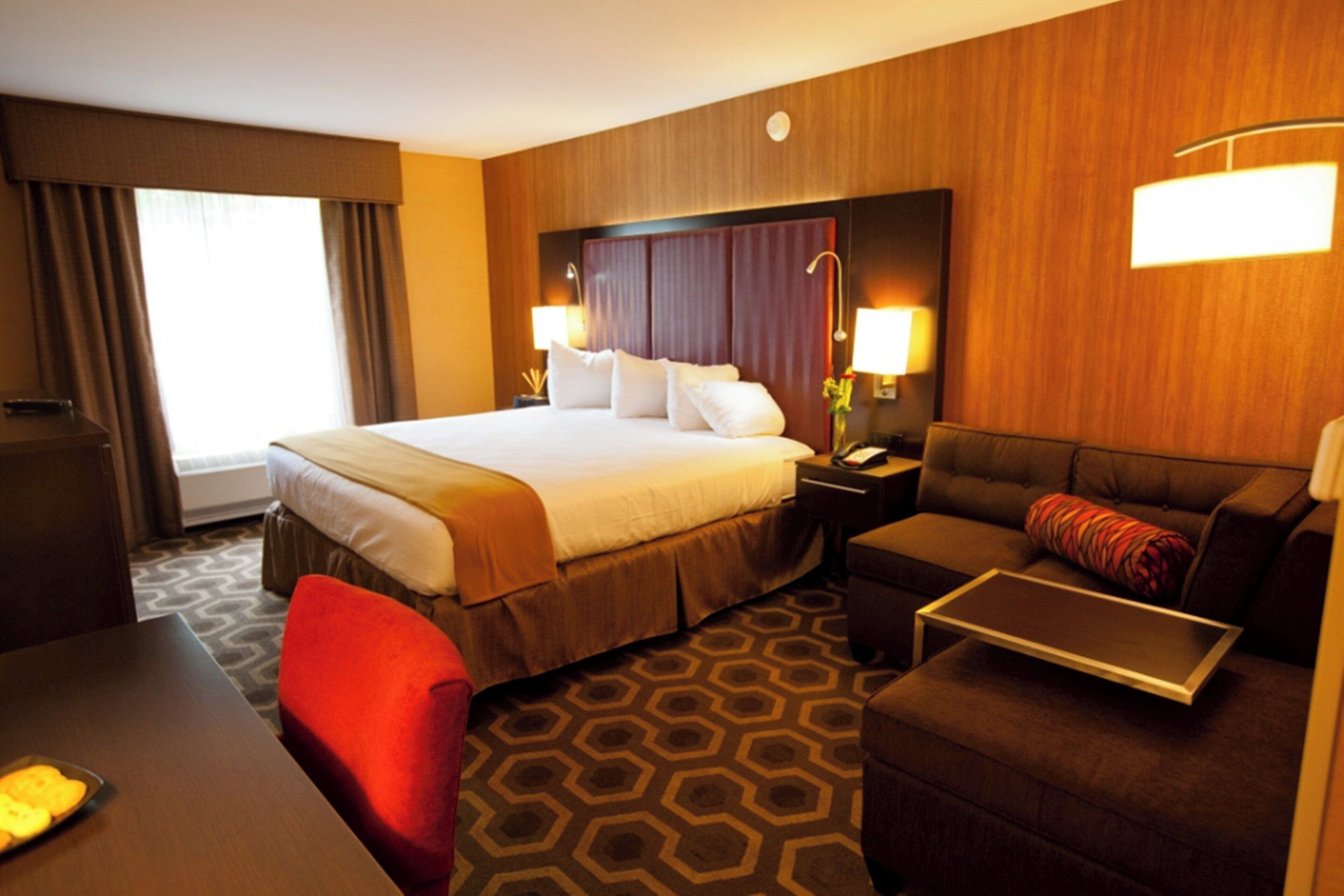 Quarto de hotel com uma cama grande, um sofá, uma escrivaninha e uma cadeira.