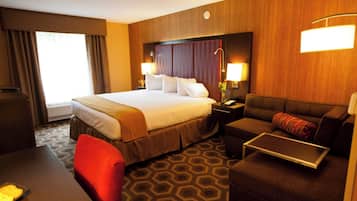 Quarto de hotel com uma cama grande, um sofá, uma escrivaninha e uma cadeira.