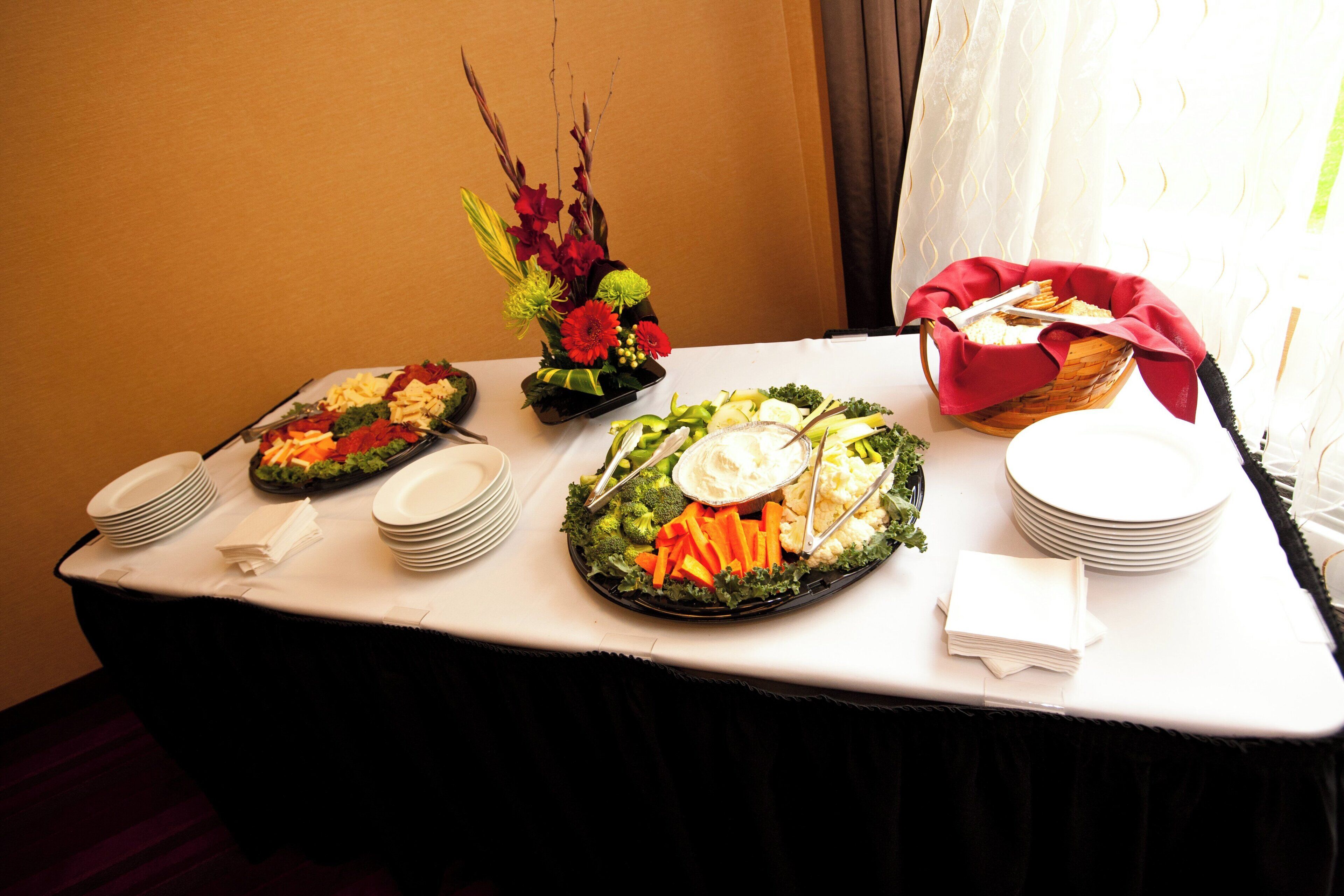 Una mesa de buffet con diversos platos, entre ellos ensaladas, verduras y un cuenco de fruta.