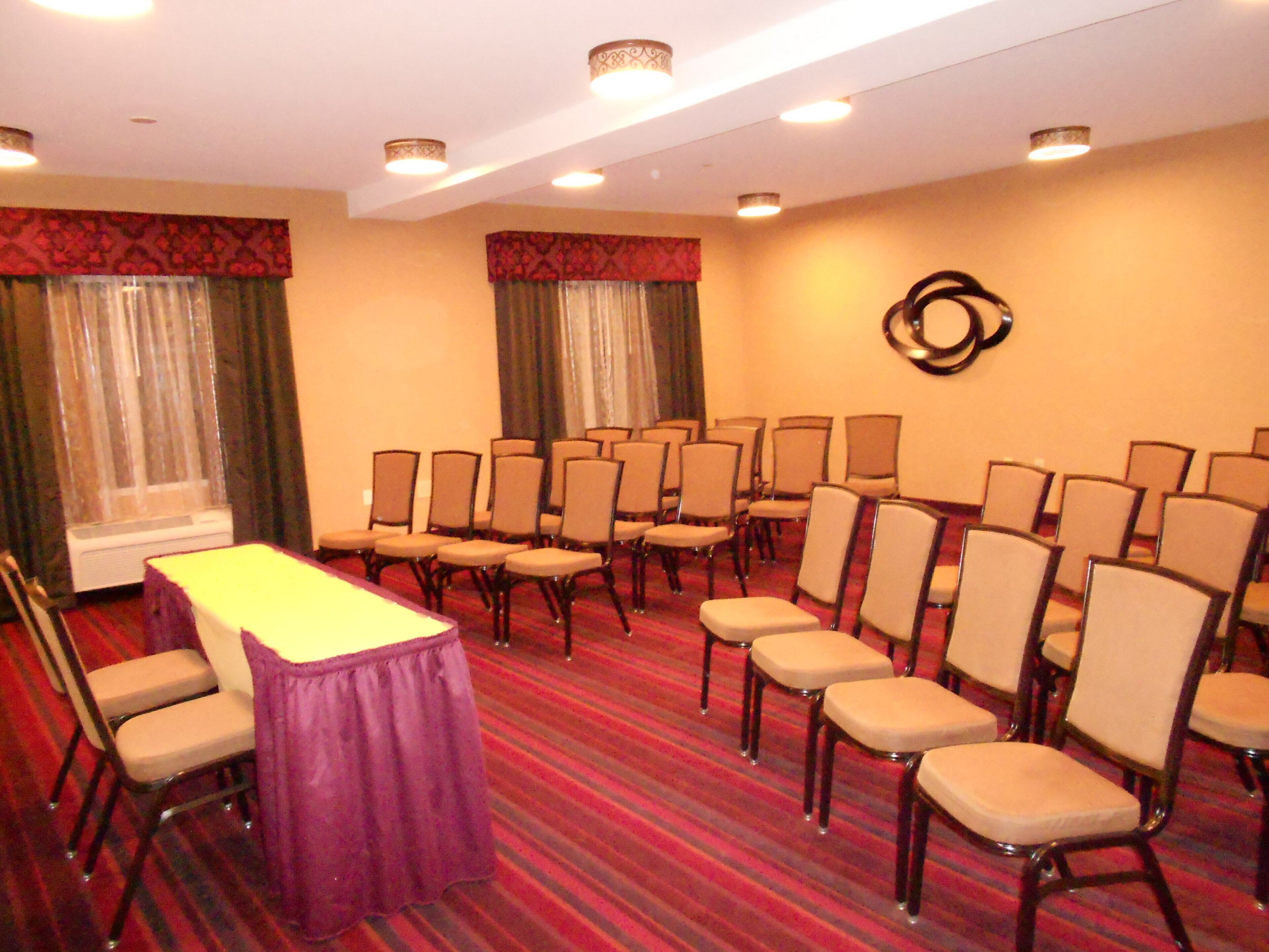 A conference room with a long table, multiple chairs, and a carpeted floor.