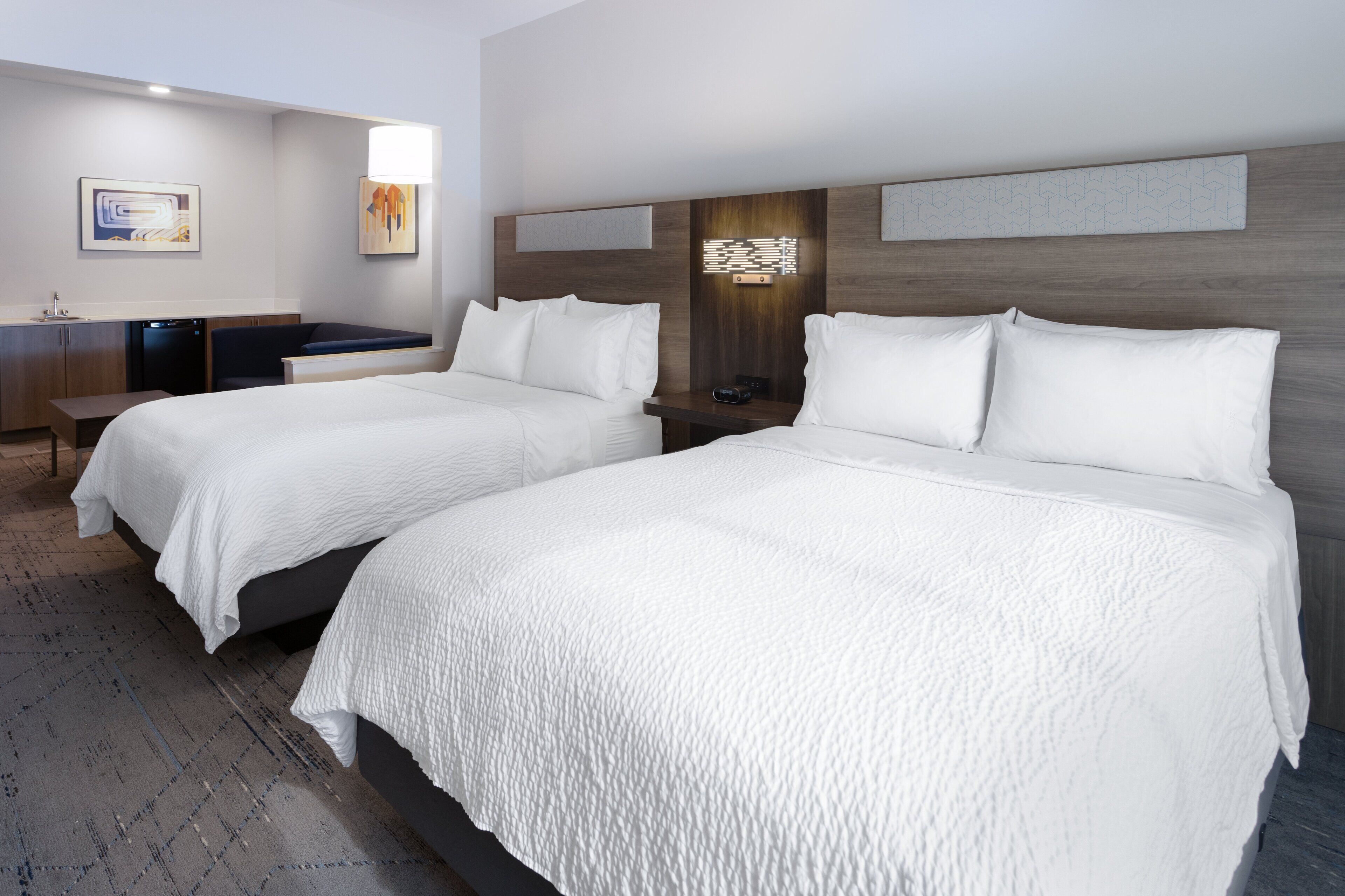 A hotel room with two beds, a desk, and a seating area.