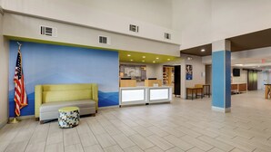 A lobby with a reception desk, a sofa, a small round table, and an American flag. - Holiday Inn Express & Suites Orangeburg by IHG (Orangeburg)