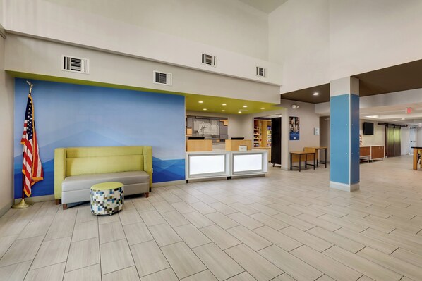 A lobby with a reception desk, a sofa, a small round table, and an American flag. - Holiday Inn Express & Suites Orangeburg by IHG (Orangeburg)