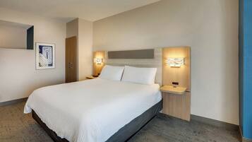 Een moderne hotelkamer met een groot bed, een houten hoofdbord en twee nachtkastjes met wandlampen.