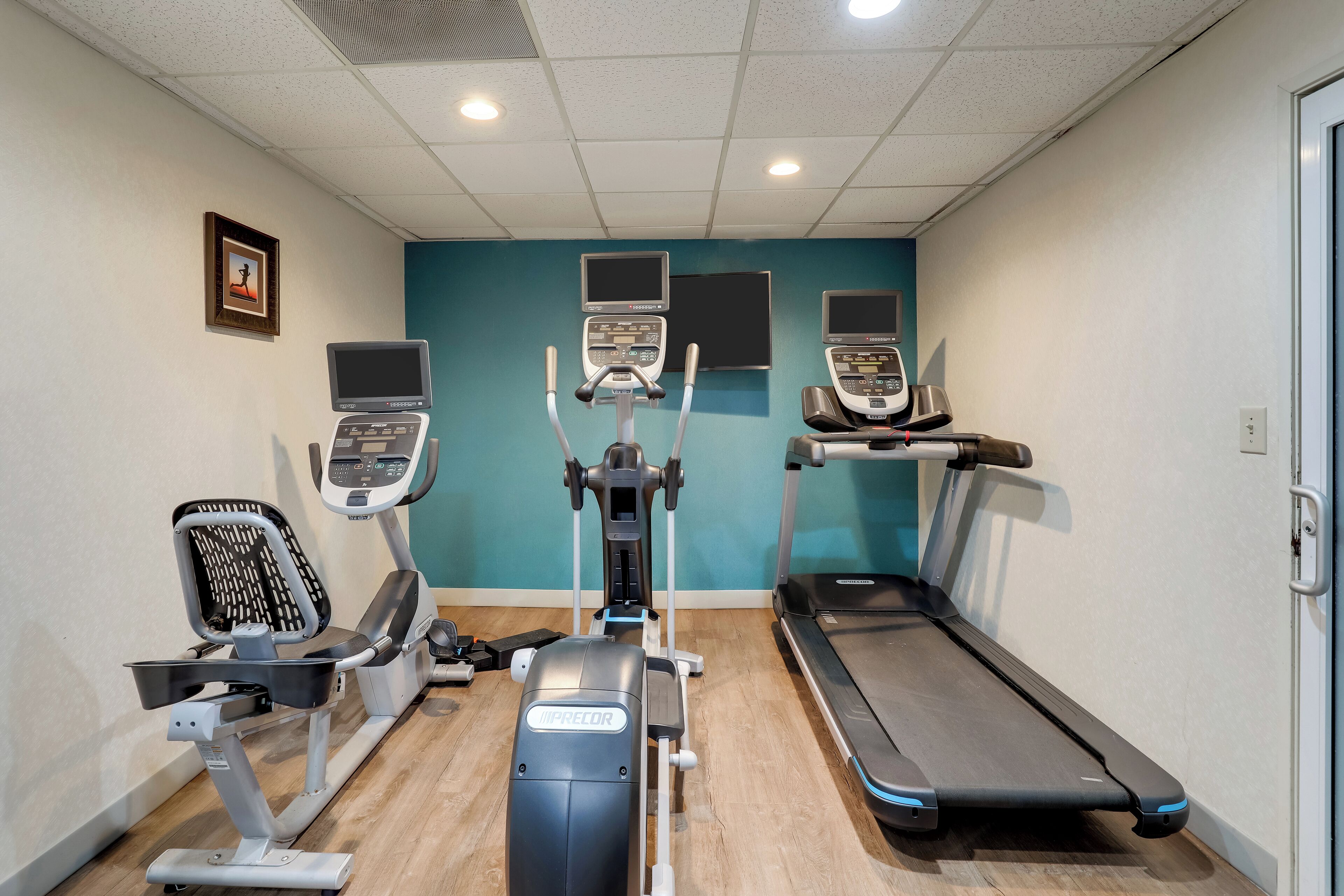Un gimnasio con cintas de correr, elípticas y una bicicleta estática.