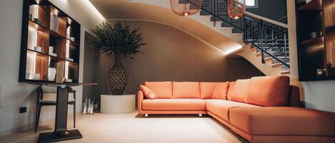 A modern living room with a curved staircase, a sectional sofa, and a bookshelf.