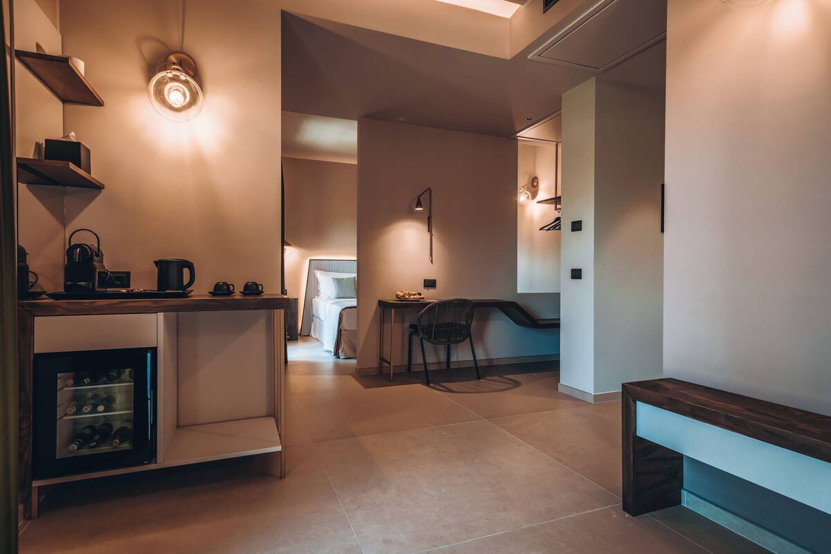 Una cocina moderna con un enfriador de vino empotrado, una cafetera y un comedor con banco y silla.