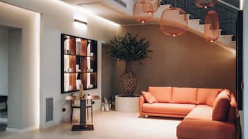 A modern living room with a sectional sofa, a wooden bookshelf, a round table, and a large vase with a plant.