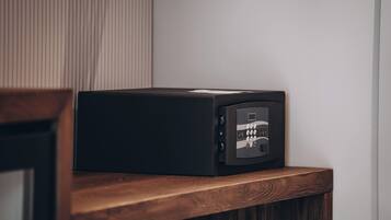 A black safe on a wooden shelf against a white wall.