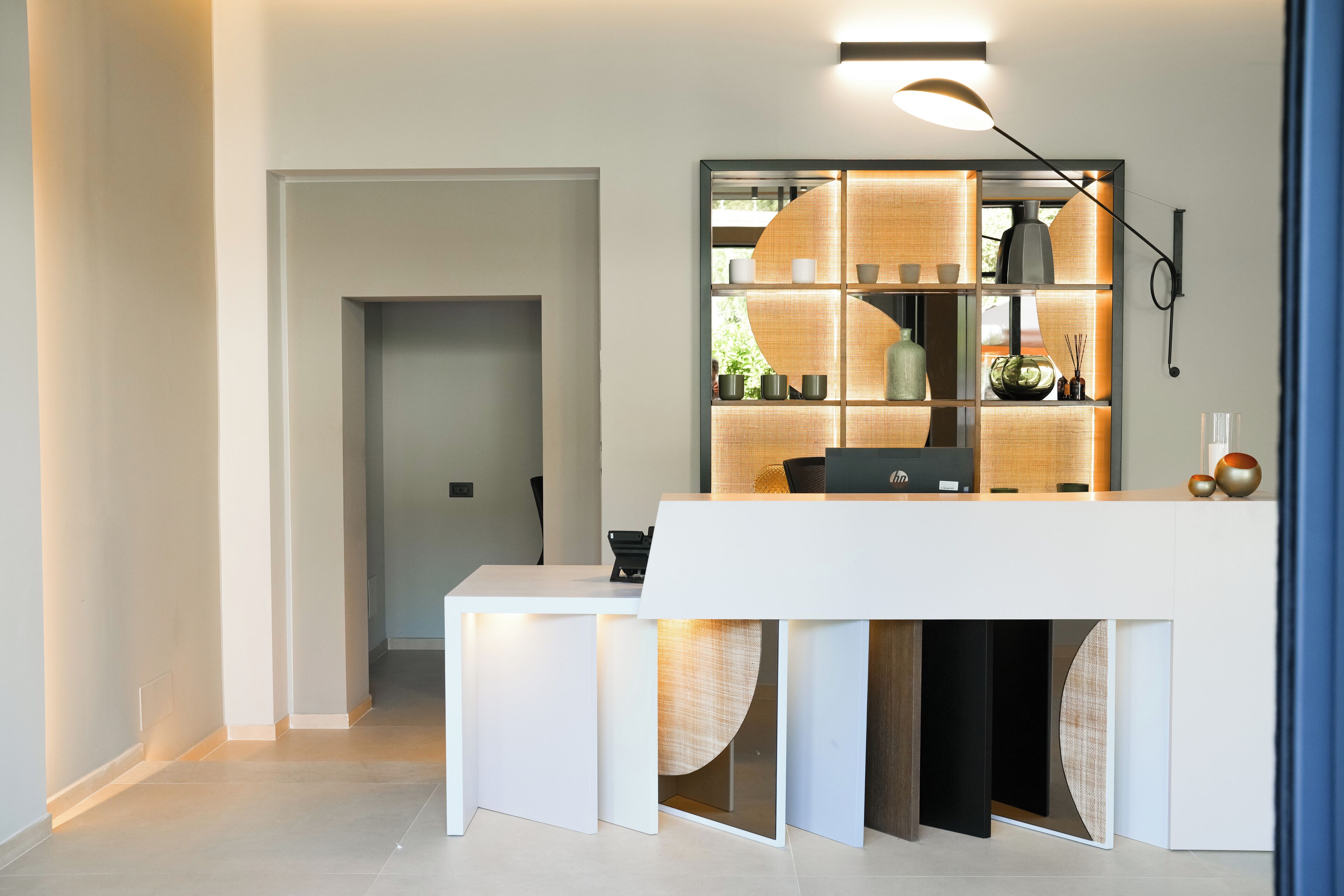 A modern reception desk with a built-in shelving unit, a pendant light, and a view into the adjacent room.