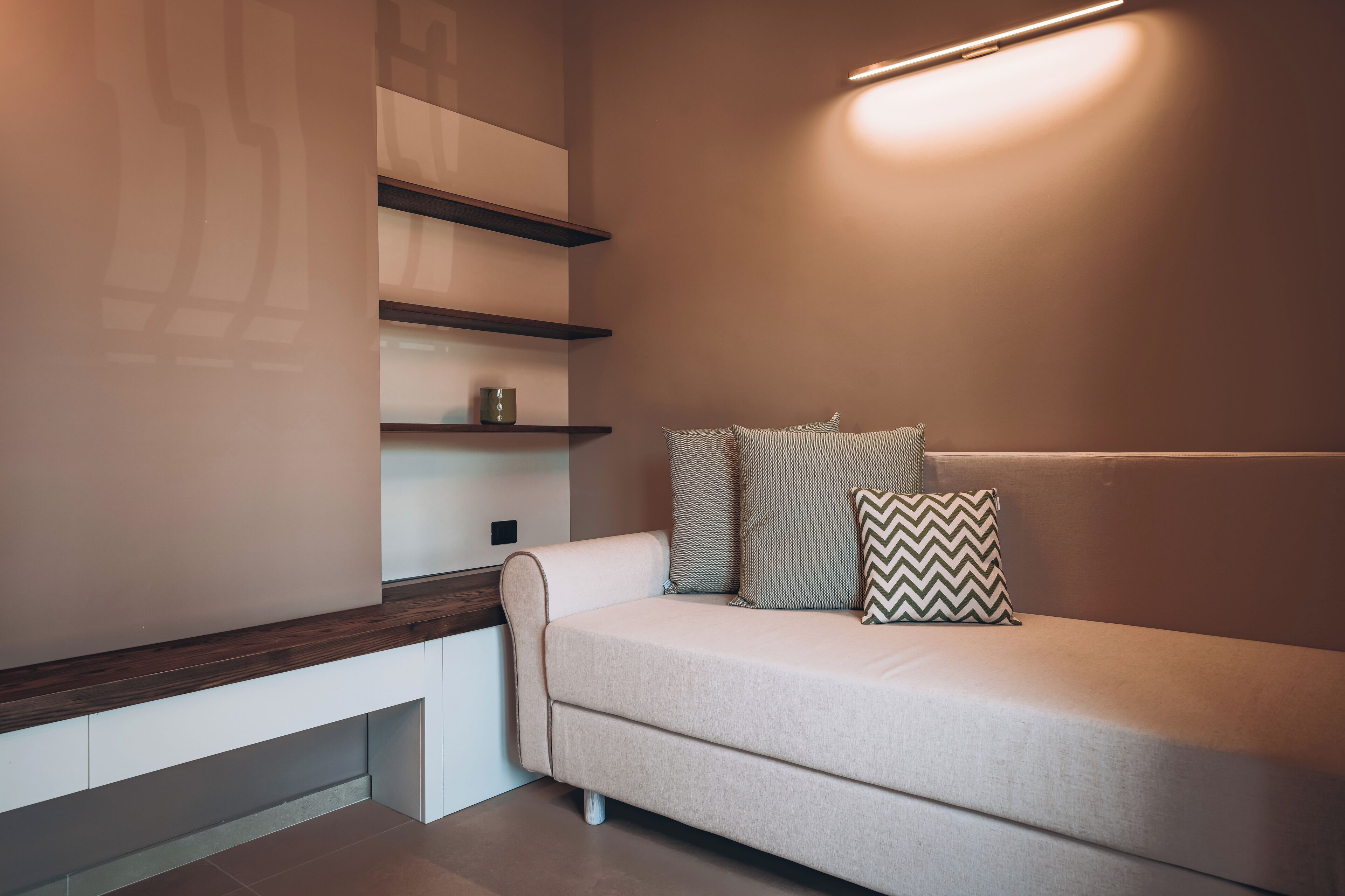 A modern living room with a sofa, cushions, and built-in shelves.