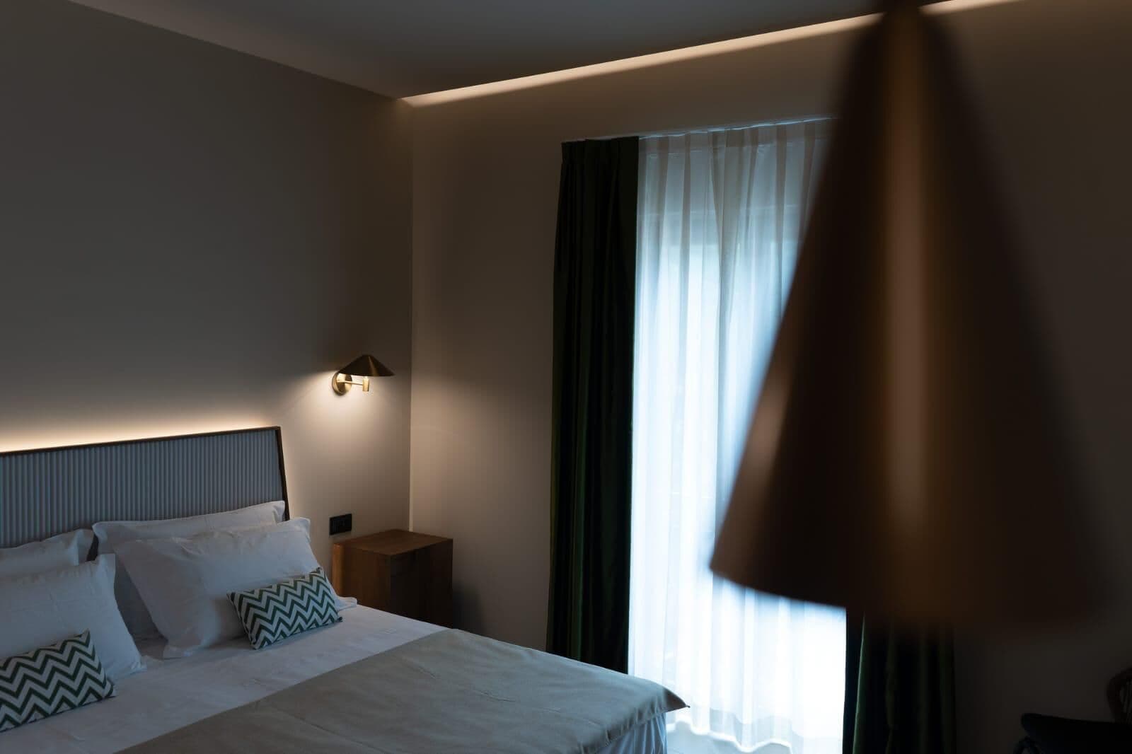 Ein Hotelzimmer mit Bett, Nachttisch und Lampe.