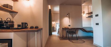 Una cocina moderna con refrigerador integrado, una cafetera y un comedor con una silla y mesa.