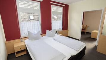 Una habitación de hotel con dos camas, una mesita de noche de madera, un escritorio y una silla.