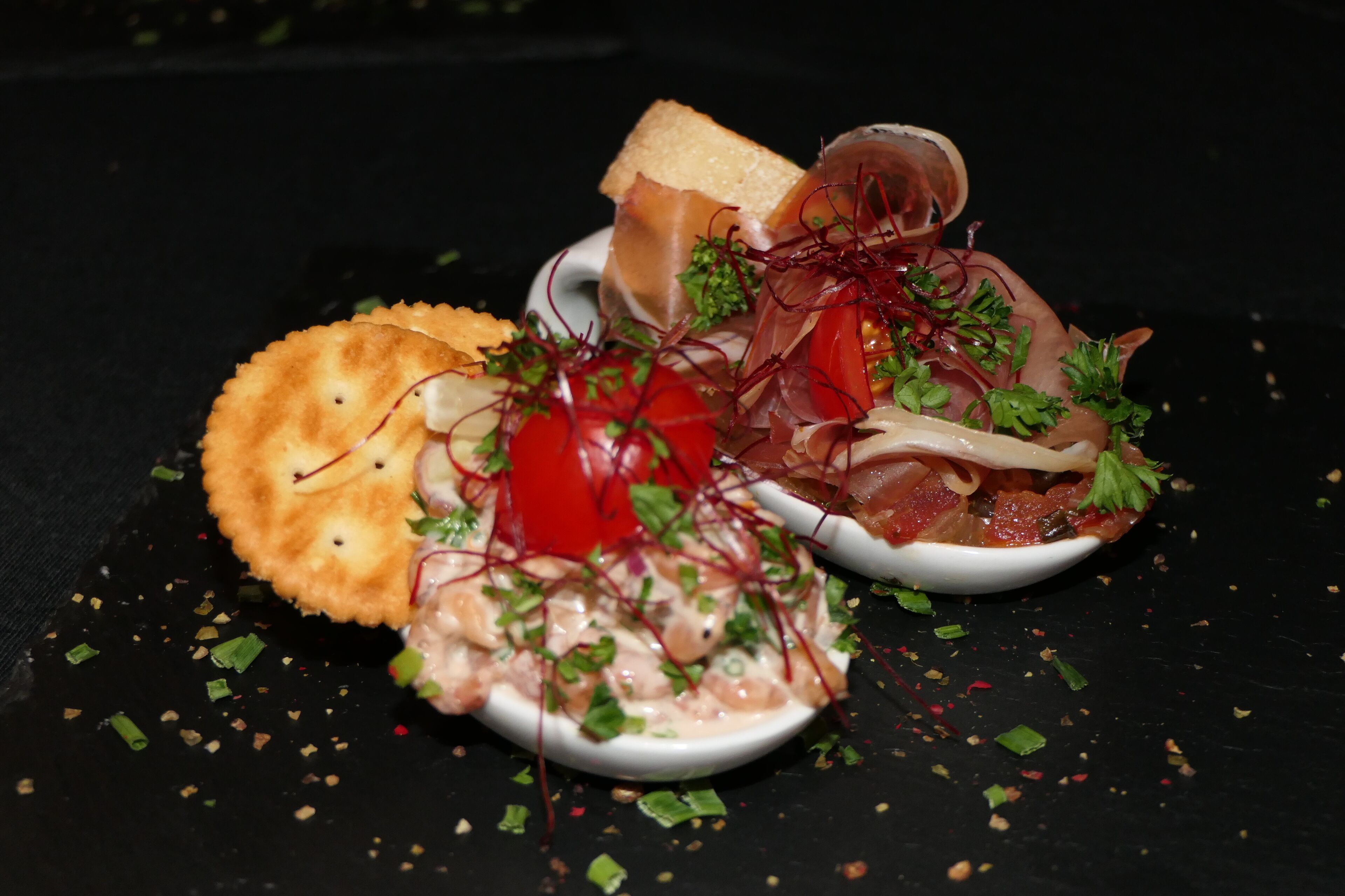 A dish with seafood, vegetables, and bread on a black surface.