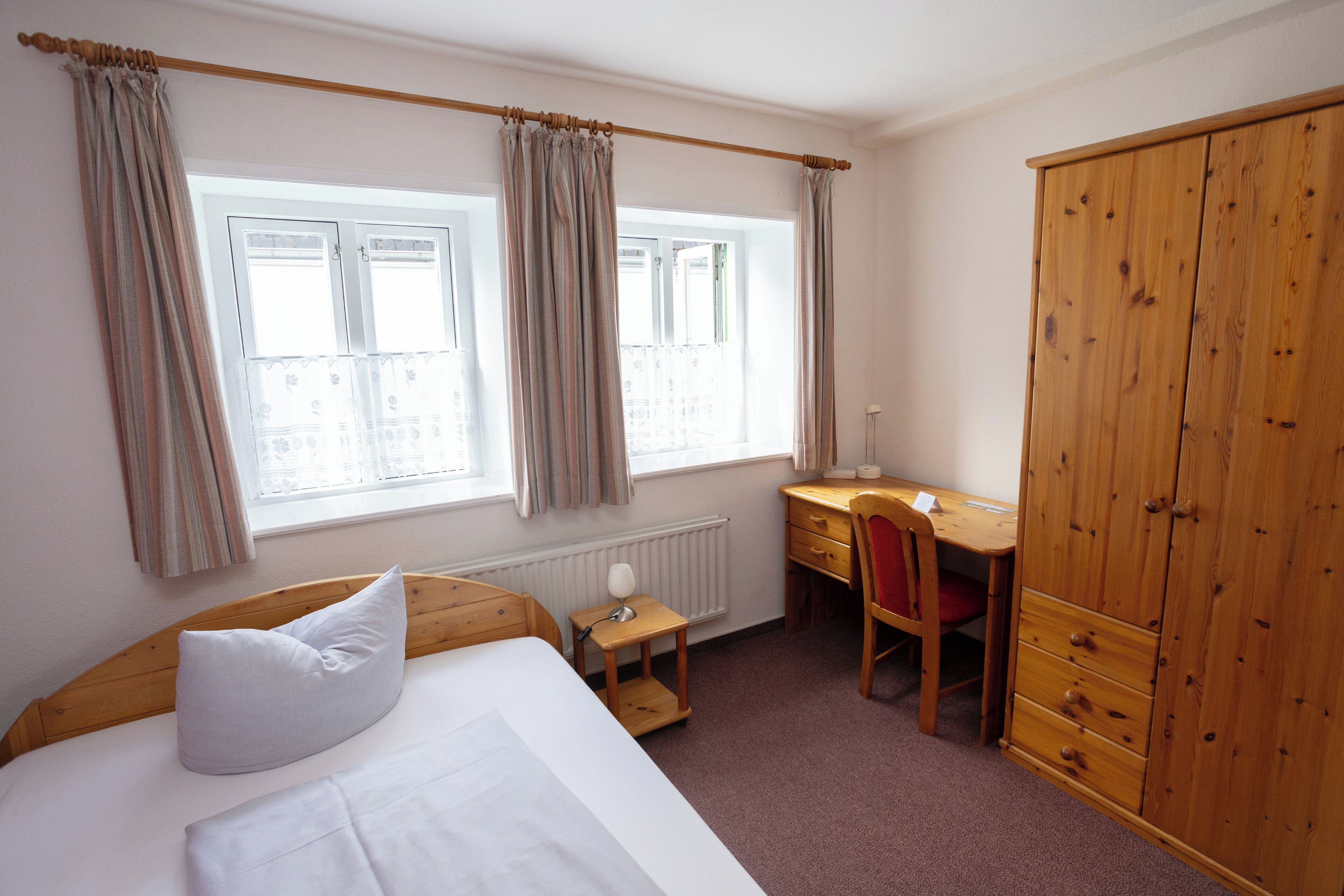 A bedroom with a bed, a desk, a chair, and a wardrobe.