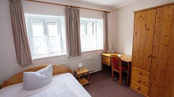 A bedroom with a bed, a desk, a chair, and a wardrobe.
