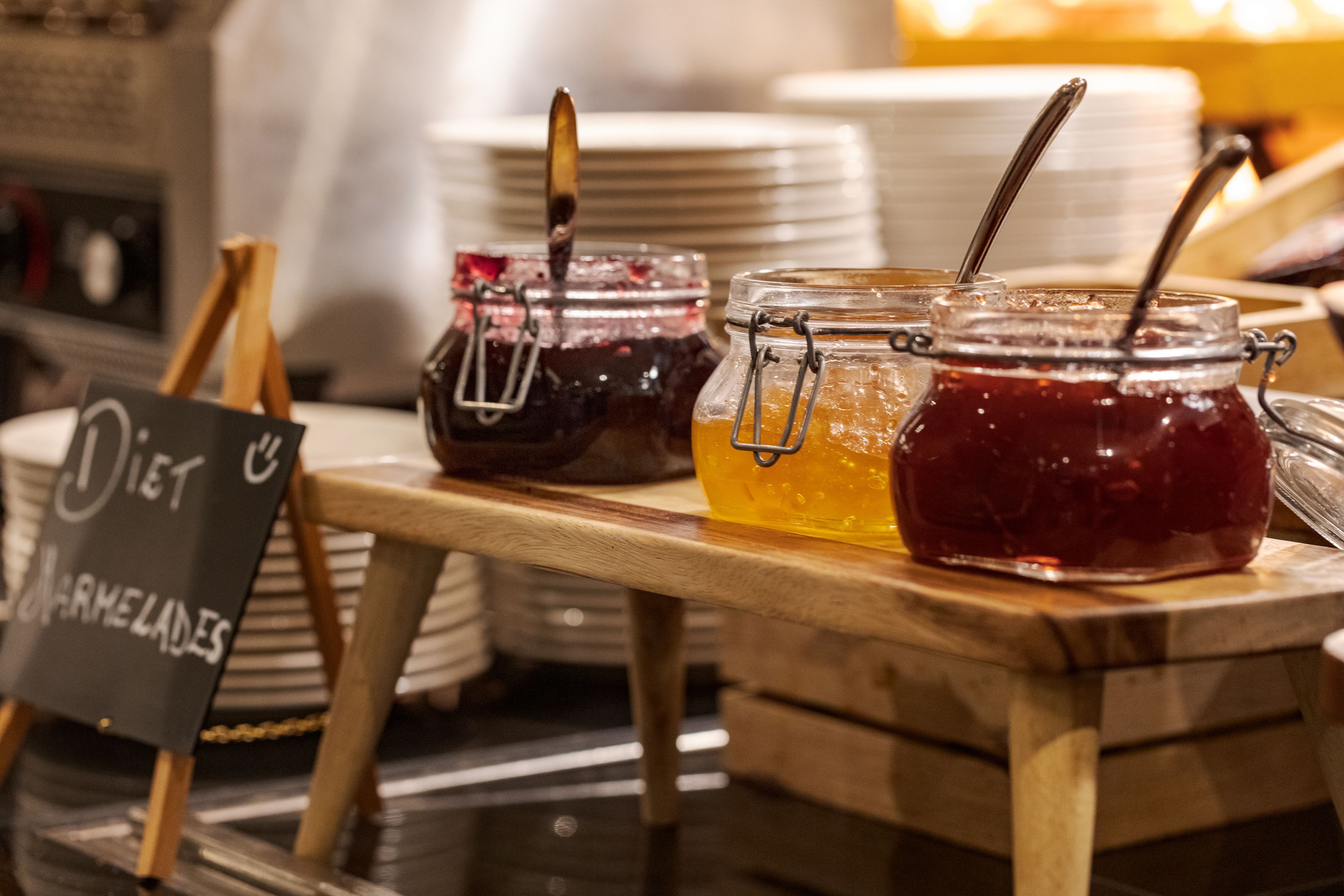 Une table de buffet avec divers pots de confitures et une pancarte indiquant les options végétaliennes.