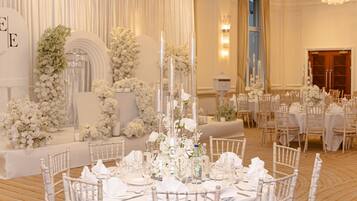 Une salle à manger élégante, avec une décoration de table blanche, des arrangements floraux et de grandes bougies.