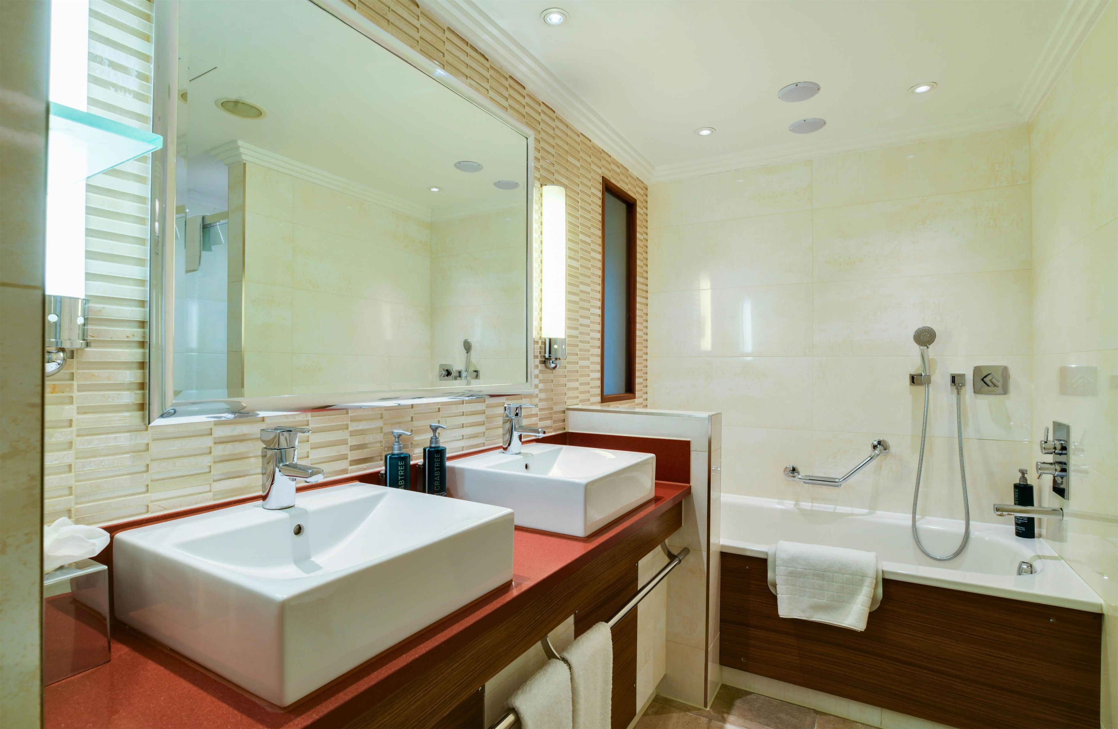 Une salle de bain moderne avec deux lavabos, un grand miroir, une douche et une baignoire.