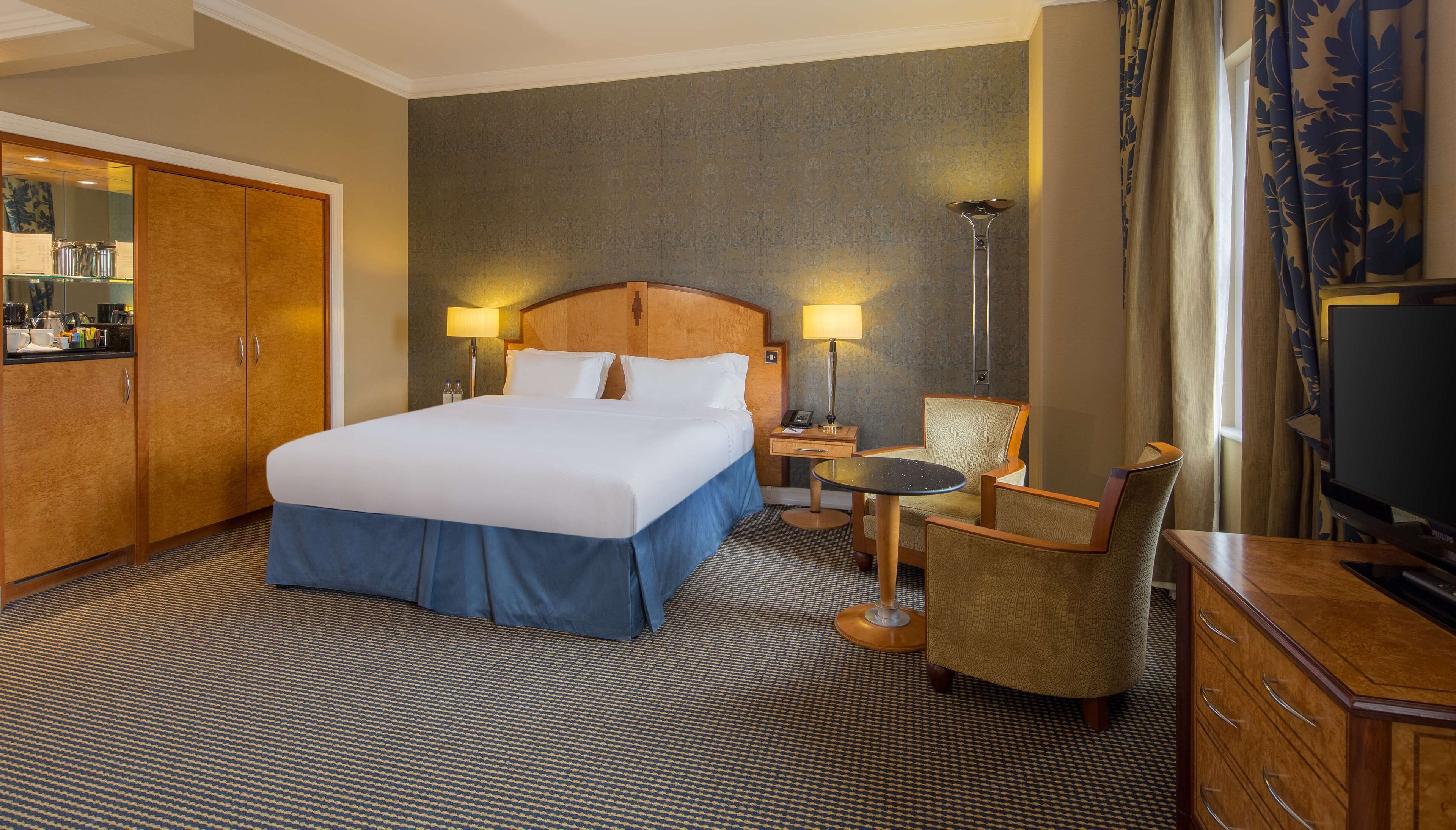 Une chambre d’hôtel avec un grand lit, un bureau avec une chaise, une télévision et un mini-bar.