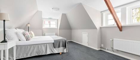 A bedroom with a bed, bedside tables, a radiator, and a window.