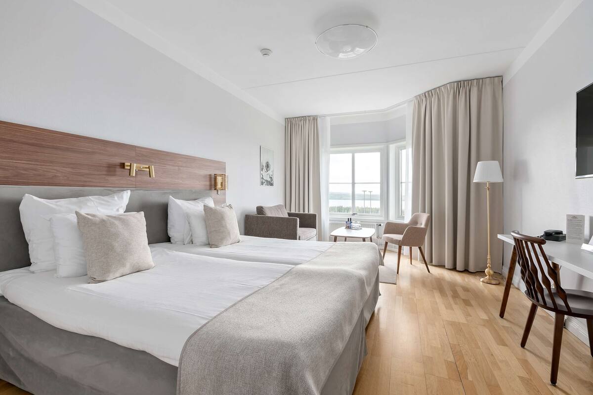 A hotel room with two beds, a desk, and a chair.