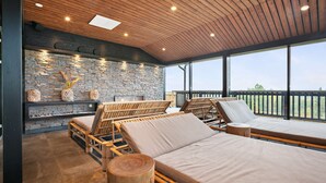 Un salon lumineux, doté d’un plancher en bois, de murs en pierre et de grandes fenêtres offrant une vue sur l’extérieur.