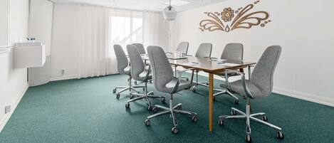 A conference room with a green carpet, white walls, and a decorative wall piece.