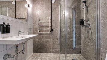 Une salle de bain moderne avec une douche à parois de verre, un lavabo blanc avec un miroir et un porte-serviettes.