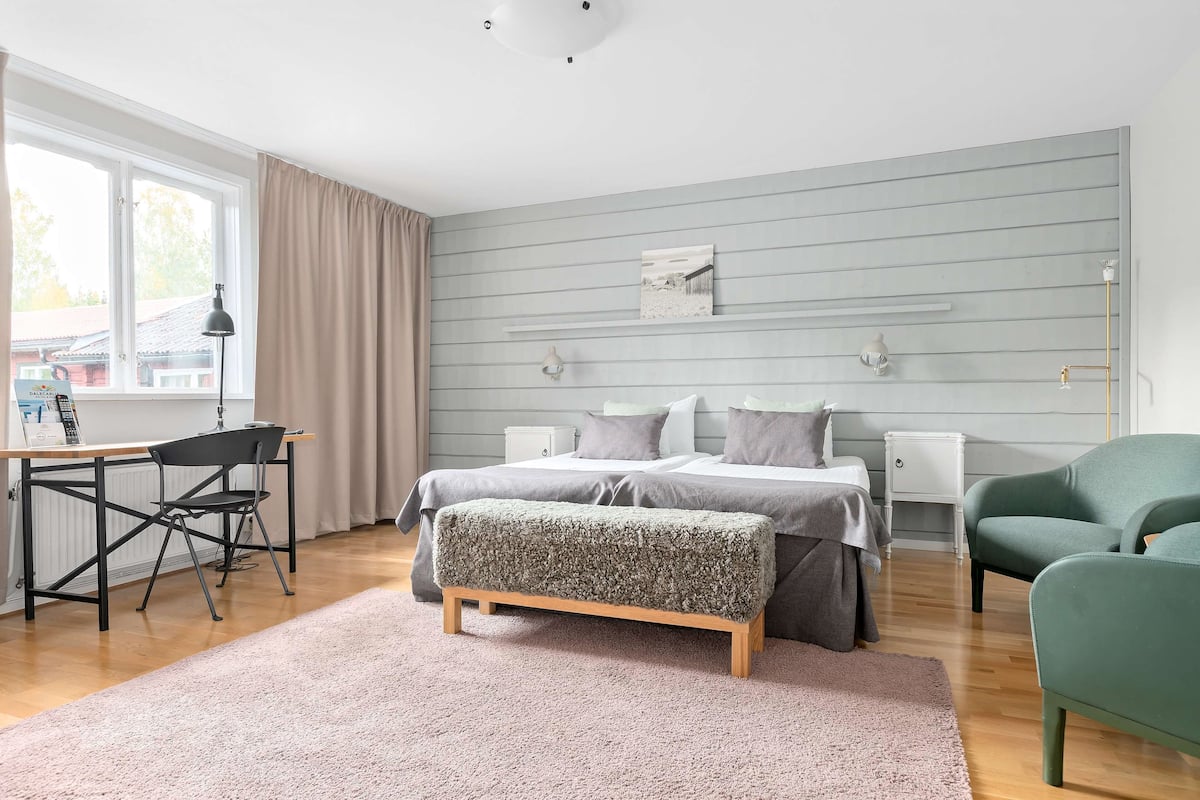 A bedroom with a bed, bedside tables, a desk, and a chair.