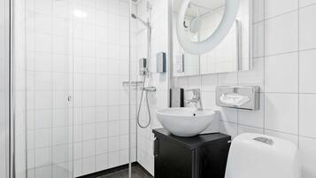 A modern bathroom with a glass-enclosed shower, a white sink, and a black vanity.