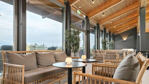 Un intérieur moderne avec des meubles en osier, de grandes fenêtres et un plafond en bois.