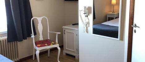 A hotel room with a bed, a chair, a small table, a mirror, a TV, and a spa menu sign.