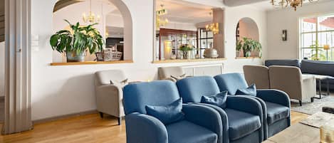A modern living room with a blue sofa set, a wooden coffee table, and a chandelier.