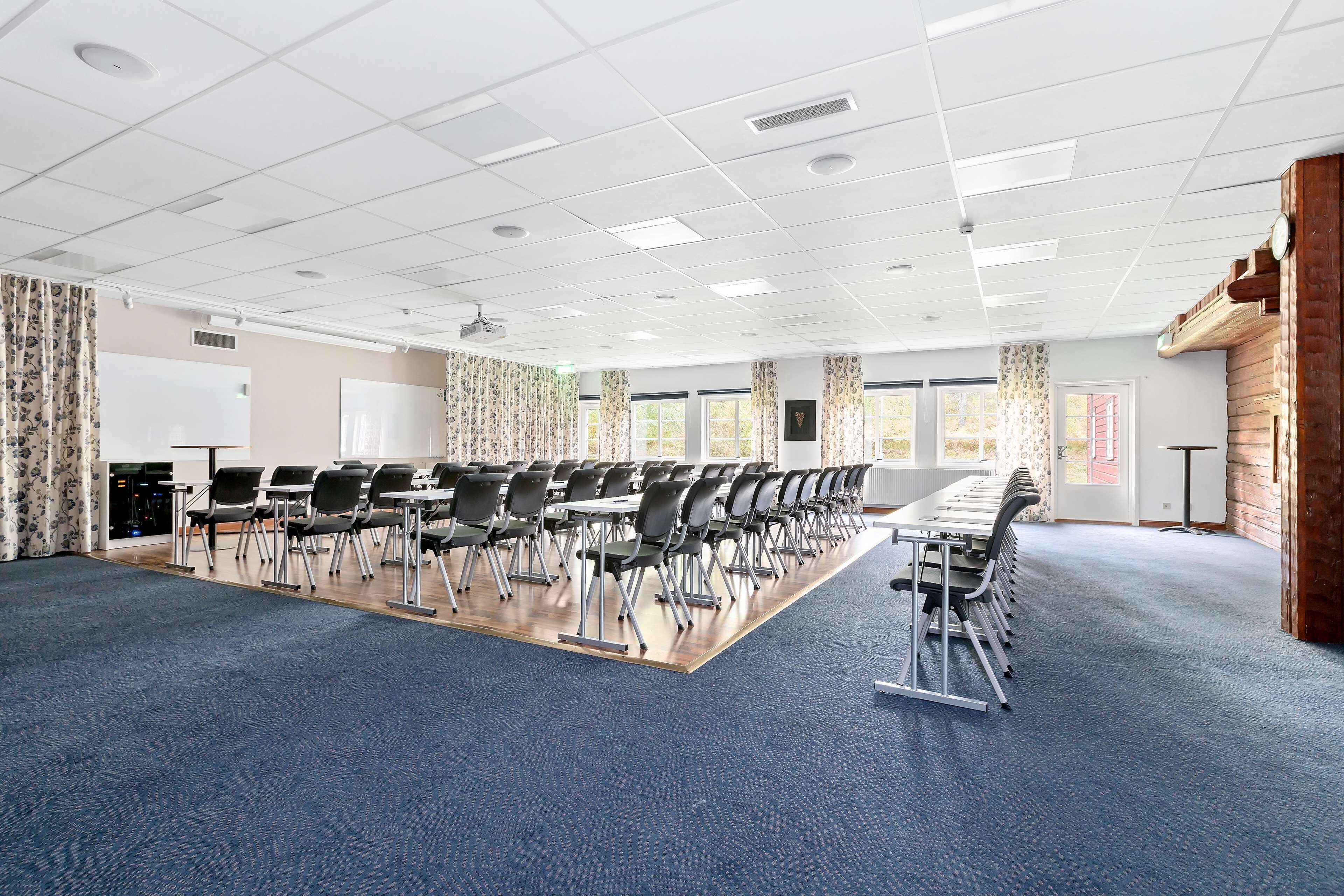 A conference room with rows of chairs, a long table, and large windows.