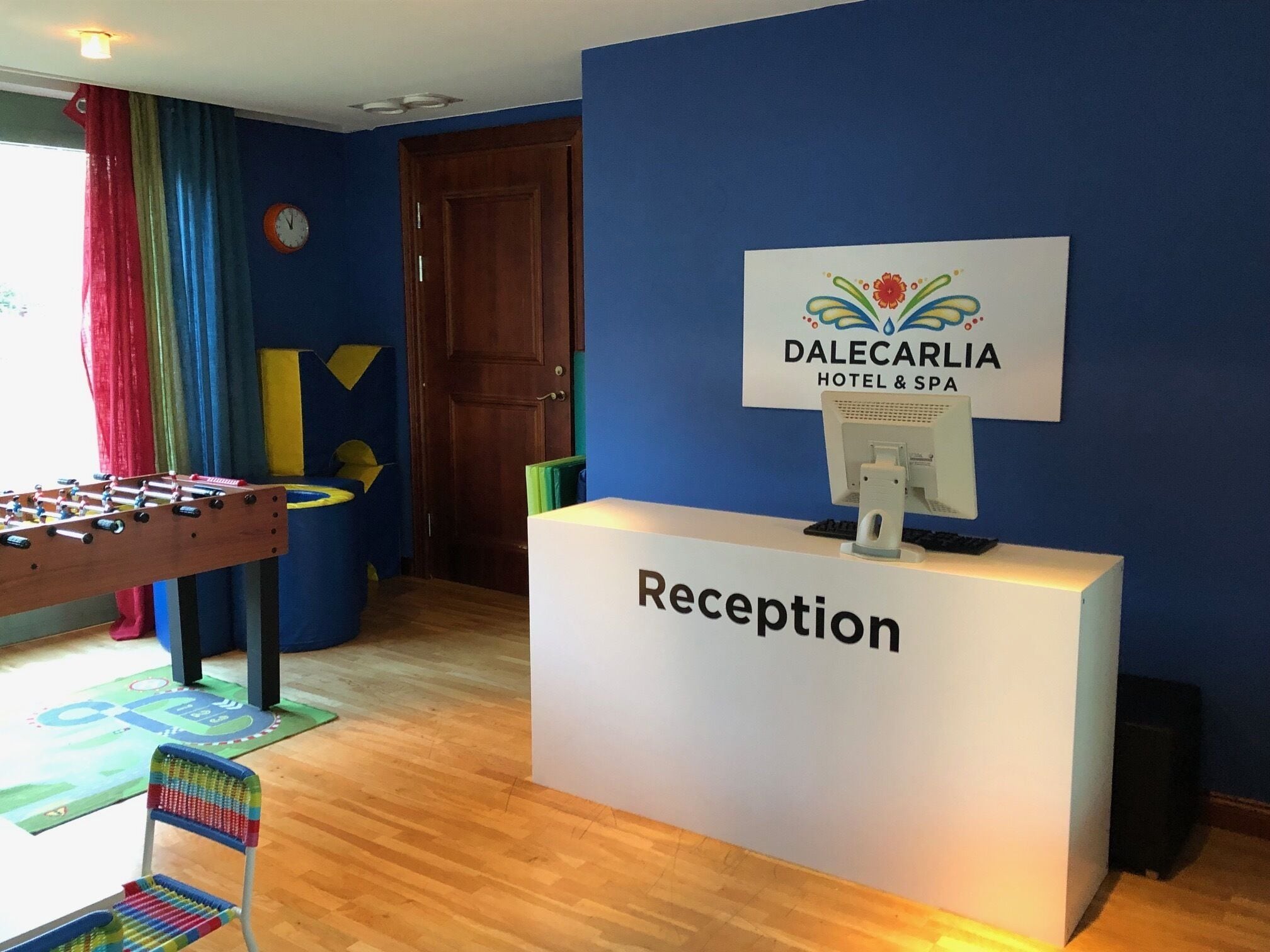 A reception desk labeled "Reception" with a computer monitor and a sign for "DALECARLIA HOTEL & SPA".