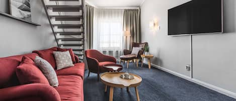 Una sala de estar moderna con un sofá rojo, una mesa de centro de madera y un televisor de pantalla plana montado en la pared.