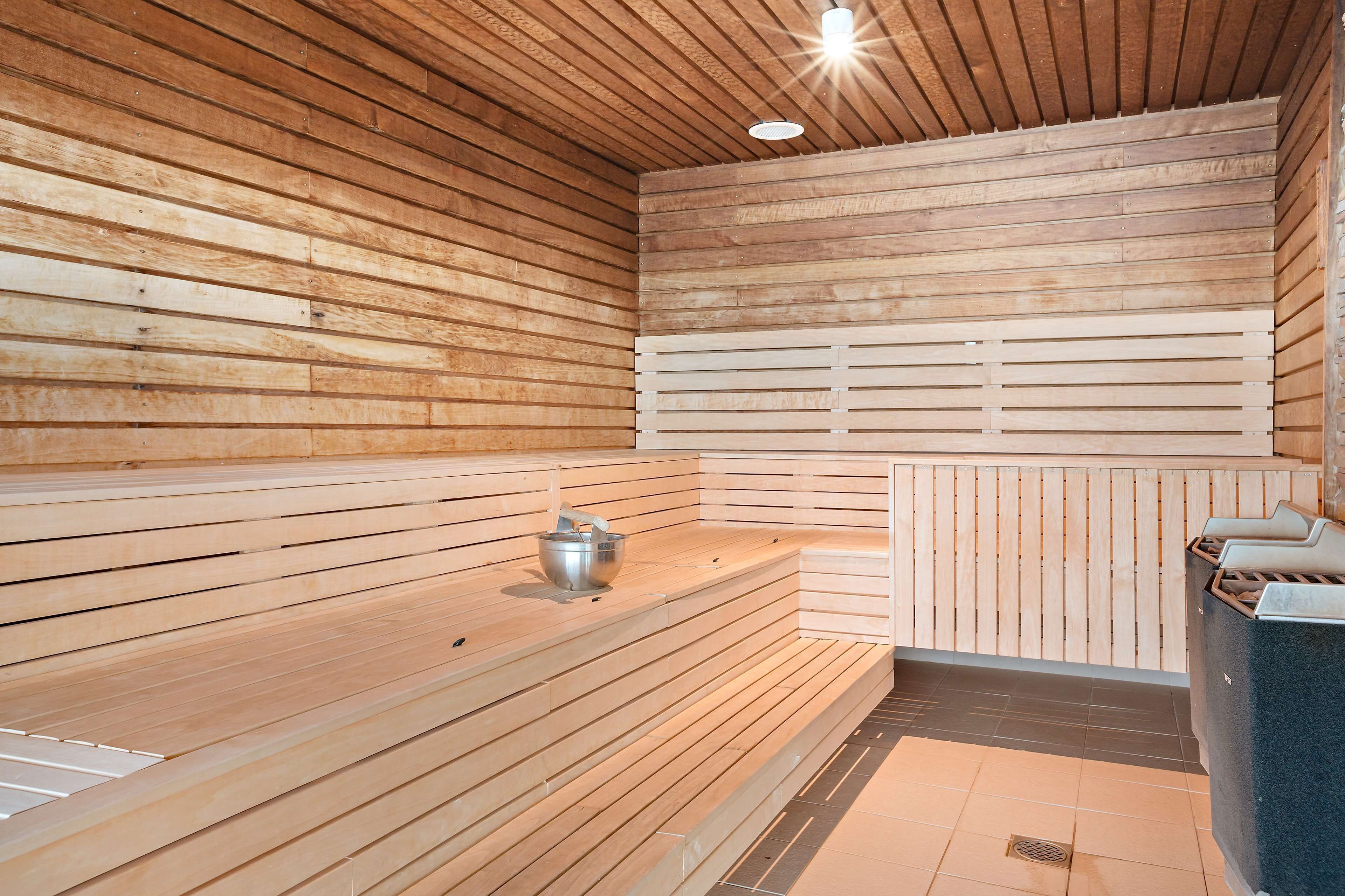 A sauna with wooden benches and a metal container.